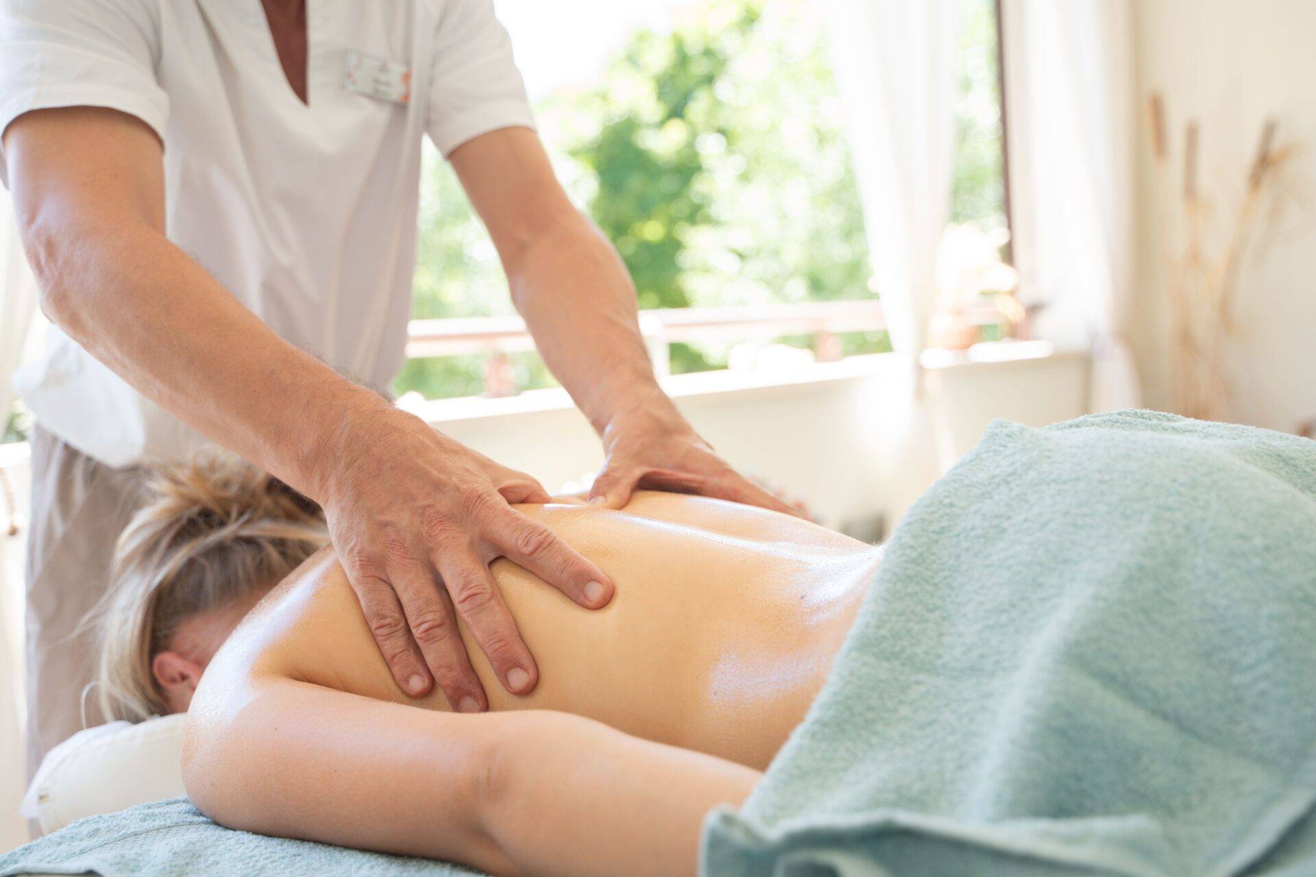 Operatore esegue un massaggio alla schiena di una donna distesa sul lettino nella terrazza wellness del Camping Dei Fiori.