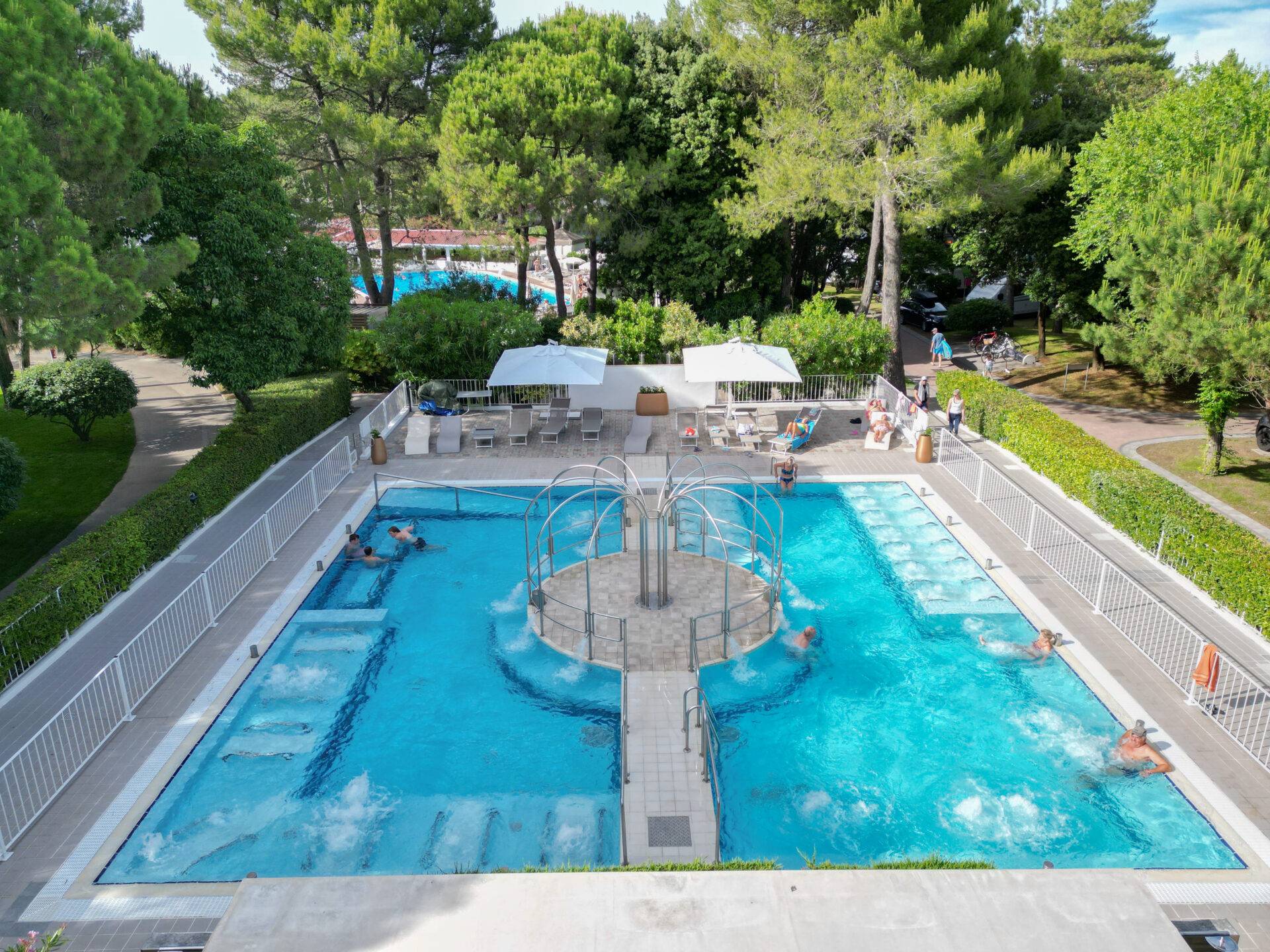 Piscina idromassaggio del Camping Dei Fiori vista dall'alto, con getti d'acqua, ospiti e lettini nell'area relax.